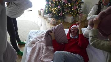 People at holiday party have a pillow fight wearing santa hats and laughing in slow motion video