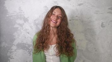 Young woman with long red curly hair laughs looking toward camera