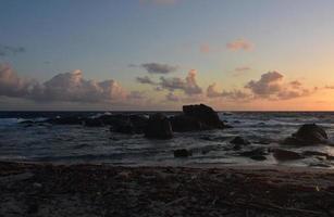 Sun Rising Over Large Rock Formations in the Ocean photo