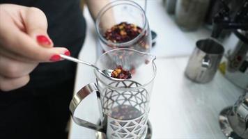 Loose leaf tea is sprinkled into a glass press for steeping video