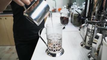 varm vatten är hällde in i glas Tryck över lösa blad te till brant video