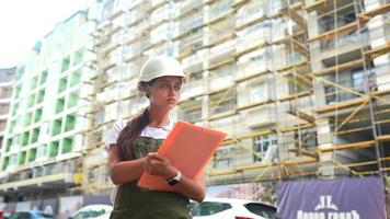 mulher de capacete branco na zona de construção pensa e olha ao redor e sorri video