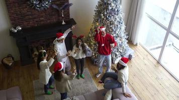 Menschen auf einer Weihnachtsfeier feiern und tanzen zusammen mit Weihnachtsmützen und Getränken video