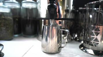 el agua caliente se vierte en una taza de vapor de leche de acero inoxidable