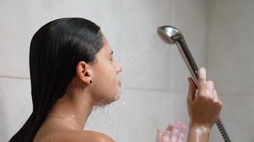 Woman in shower rinses face and hair in slow motion video