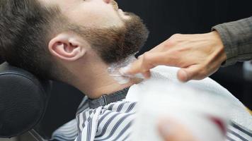 Barber applies shaving cream to seated client's neck video