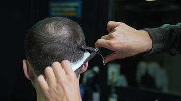 Barber trims back of head hair with comb and thinning shear scissors