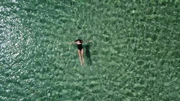 zoom aérien d'une femme plongeant et nageant dans une eau cristalline video