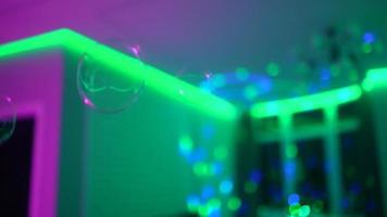 Bubbles float around in a dark room with multicolor lights video