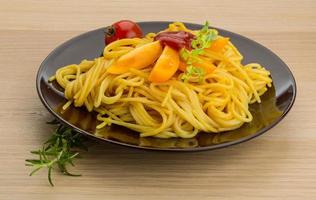 Vegetarian pasta on the plate and wooden background photo