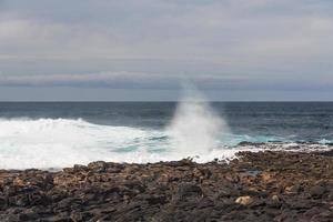 Turbulent ocean waves with white foam beat coastal stones photo