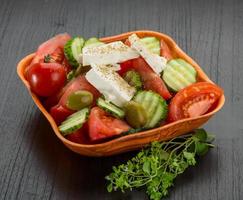 Greek salad in a bowl on wooden background photo