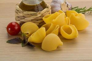 Raw pasta on wooden background photo