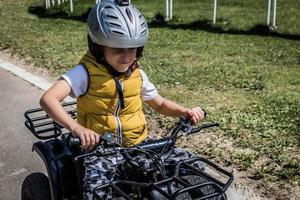 niño pequeño disfrutando mientras conduce quads en la naturaleza. foto