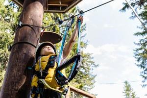 Small boy attaching carabiner to zip line on canopy tour in the forest. photo