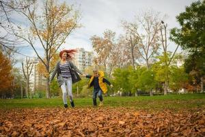 Mother and son holding hands and running in the park. photo