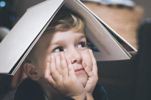 Close up of kid with a book on his head. photo