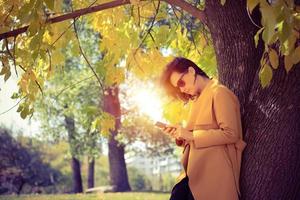 Beautiful woman using mobile phone in the park. photo