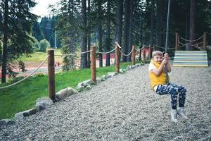 niño juguetón divirtiéndose mientras hace tirolesa en la naturaleza. foto