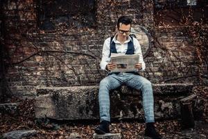 Retro-styled man relaxing outdoors while reading newspaper. photo