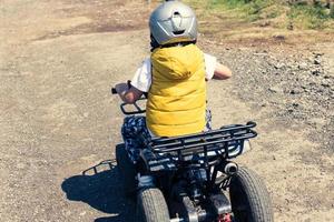 Rear view of kid driving off road vehicle. photo