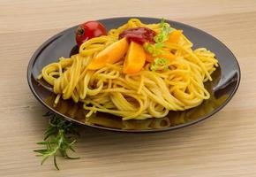 Vegetarian pasta on the plate and wooden background photo