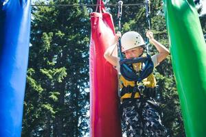 Small boy getting through obstacles in adventure park. photo