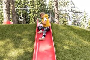 Kid sliding down and having fun in the park. photo