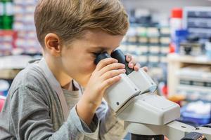 Small boy looking through microscope in laboratory. photo