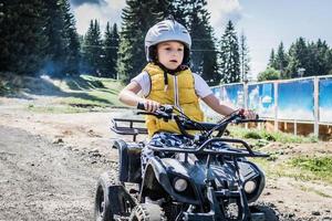 Little boy driving atv vehicle on off road track. photo