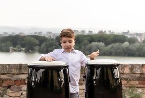 Carefree kid playing bongos by the river. photo
