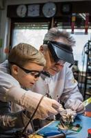 Teacher and small boy soldering mother board during IT class. photo