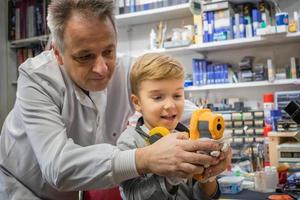 Small boy using infrared thermometer with help of a teacher. photo