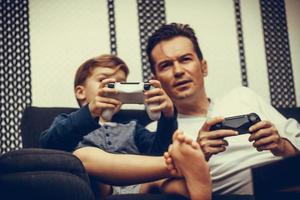 Small boy and hi father playing video games together. photo