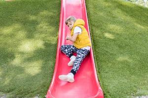 niño deslizándose mientras pasa un día en el parque. foto