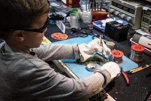 Little engineer repairing circuit board in IT laboratory. photo