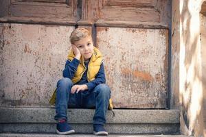 Thoughtful boy sitting on steps. photo