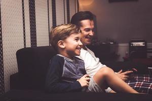 Happy kid enjoying in playing video games with his father. photo