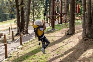 Carefree kid having fun while rappelling from zip line in nature. photo