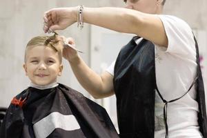 niño pequeño durante el corte de pelo en la peluquería. foto