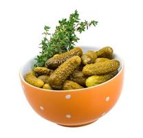 Marinated cucumbers in a bowl on white background photo