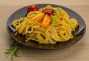 Vegetarian pasta on the plate and wooden background photo