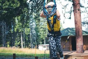 Kid walking on a zip line while being on canopy tour. photo