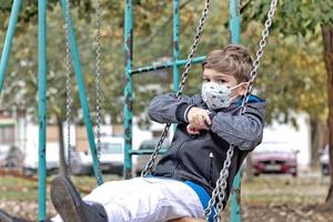 Small boy swinging at the playground during coronavirus pandemic. photo