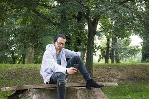 mensajes de texto de hombre sonriente mientras disfruta de la hora del café en el parque. foto