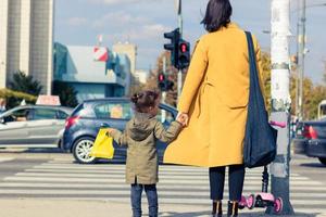 Rear view of daughter holding mother's hand on zebra crossing. photo