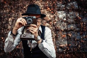 Photographer using retro photo camera while taking picture outdoors.