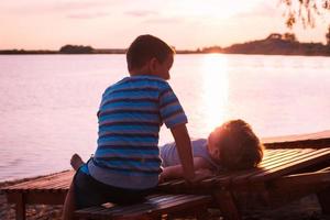 Small boys relaxing on beach at sunset. photo