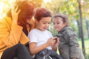 Happy family using mobile phone in the park. photo