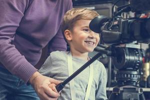 Happy boy learning how to become camera operator. photo
